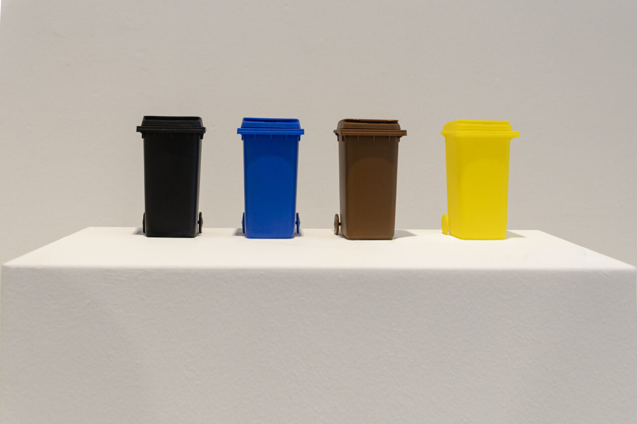 4 aufgestellte Miniatur Mülltonnen als Symbol für typisch deutsche Sauberkeit.
